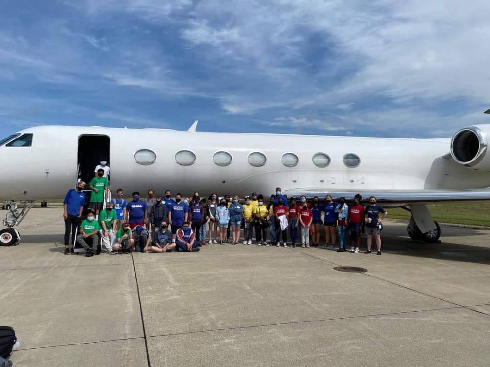 Group photo of campers outside an airplane